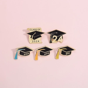 Detail of five 2024 graduation cap enamel pins in black and gold with colorful tassels