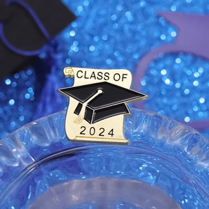 Macro shot of 2024 graduation badge with black enamel mortarboard and scroll detail