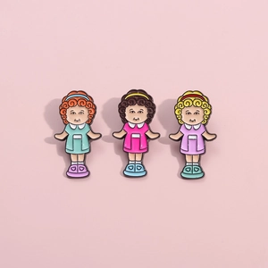 Detailed view of three colorful cartoon girl enamel pins on a soft pink background