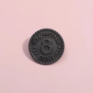 Vue détaillée du badge métallique gris foncé avec chiffre 8 et texte en relief