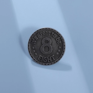 Gros plan sur un badge en métal gris mat avec numéro 8 embossé et texte décoratif