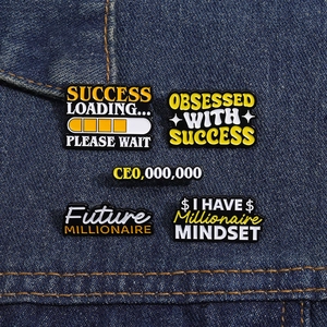 Set of 5 success-themed enamel pins with motivational quotes on blue denim fabric
