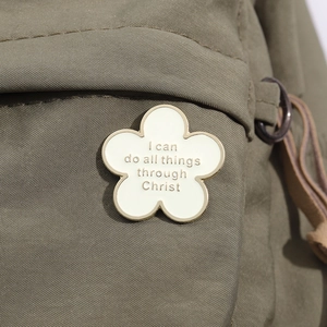 Detailaufnahme der cremefarbenen Emaille-Blume mit Motivationsspruch auf Canvas-Stoff