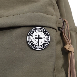 Close-up of black cross volleyball badge with Philippians 4:13 verse on green canvas bag