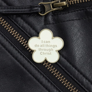 Weiße Blumen-Emaille-Brosche mit Motivationsspruch auf schwarzem Lederjacken-Hintergrund
