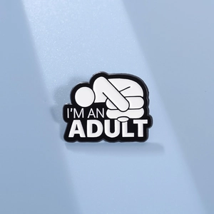 Détail de la broche créative en émail avec texte I'M AN ADULT sur une surface bleue
