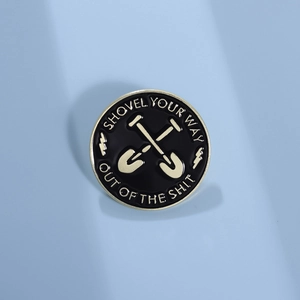 Detailed close-up of a circular gold-edged black enamel shovel pin badge with text