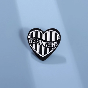 Minimalist heart-shaped enamel brooch with black white stripes and 'IT'S SHOWTIME' text
