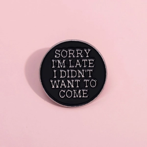 Pin's rond noir émaillé avec texte Sorry I'm Late sur un fond rose moderne