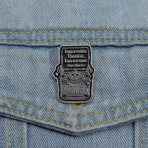 Detail shot of a vintage typewriter enamel brooch pinned on a denim jacket pocket edge