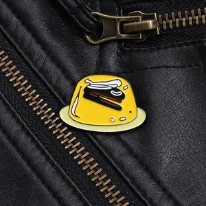 Detail shot of yellow pudding enamel pin with stapler on a black leather jacket