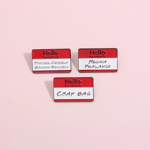 Detalle de tres pines de esmalte con nombres de la serie Friends en fondo rosa