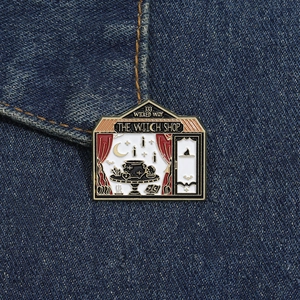 Vue détaillée du pin's émaillé The Witch Shop avec motifs magiques sur tissu denim