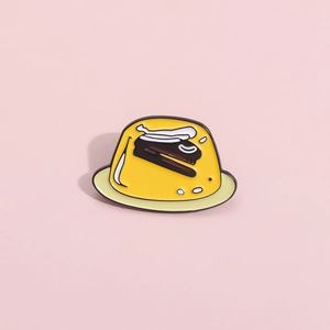Cute yellow pudding enamel pin with brown cake layer on a soft pink background