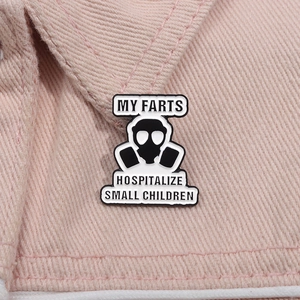 Macro detail of enamel pin featuring a gas mask design and humorous English typography