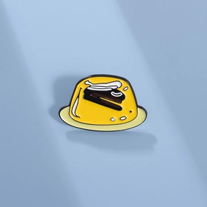Cute yellow pudding enamel brooch with black stapler pattern on a light blue background