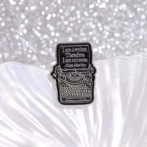 Detailed macro view of vintage typewriter enamel pin featuring Edgar Allan Poe quote