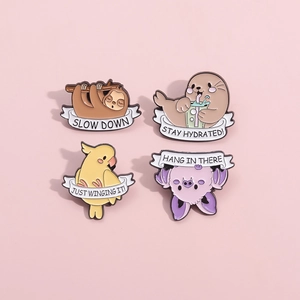 Close-up of four cute animal enamel pins with motivational quotes on a pink background