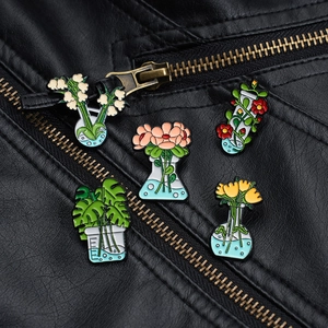 Detail of five lab flask enamel pins with flowers pinned on a black leather jacket