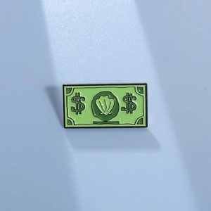 Détail d'une broche en émail vert avec un motif de monnaie dessin animé sur fond bleu