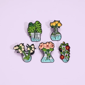 Five cartoon enamel pins featuring scientific glassware with various plants on purple background