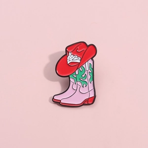 Pink cowboy boot and red hat enamel pin accessory on a clean pink background