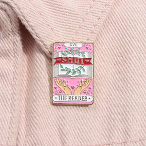 Détail du pin's en émail rose Tarot The Reader avec livre ouvert sur tissu en jean