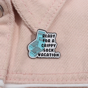 Detail showing a blue enamel pin with the quote Ready For A Grippy Sock Vacation on denim