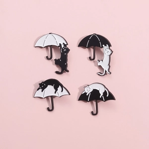 Set of four creative black and white cat enamel pins with umbrella designs on pink background