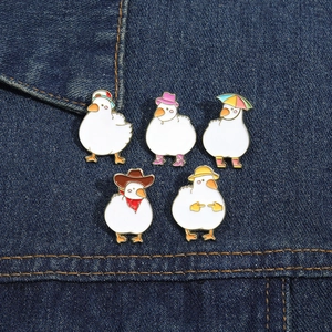 Detailed view of five cute white duck enamel pins on dark blue denim fabric background
