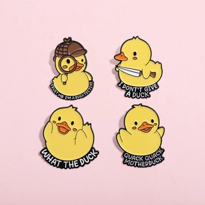 Detailed view of four cute yellow duck enamel pins on a pink background for apparel decor