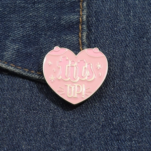 Vue détaillée du pin's cœur rose émaillé avec texte tits UP sur tissu denim bleu foncé