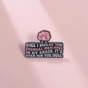 Close-up of enamel brain pin with witty text on a pink background for jacket lapel