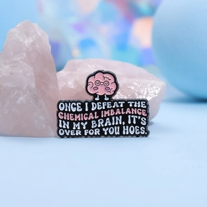 Funny pink brain enamel pin with humorous English text on a soft blue background