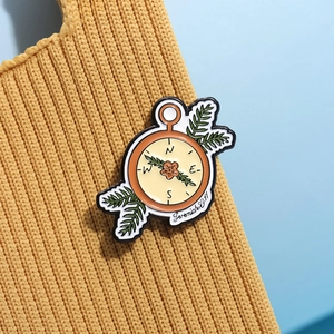 Broche boussole en émail vintage avec motif floral épinglée sur un pull en maille