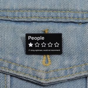 Broche en émail noir People Review amusante sur fond de tissu denim bleu