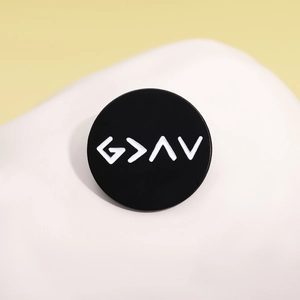 Minimalist black round enamel brooch with white G > ^ V symbols on a white stone background