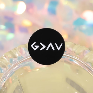 Macro shot of circular black enamel pin featuring white G > ^ V religious symbols