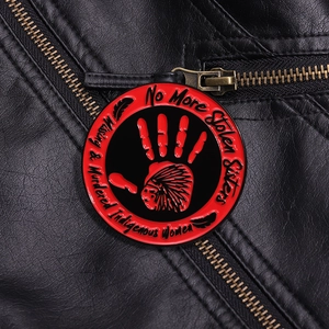 Détail du pin's émaillé empreinte rouge sur veste en cuir avec texte commémoratif