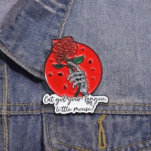 Enamel pin featuring a skeleton hand holding a red rose on a denim jacket background