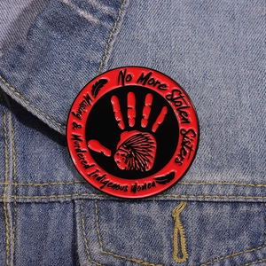 MMIW No More Stolen Sisters enamel pin with red handprint on blue denim jacket