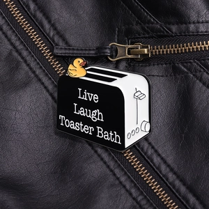 Détail macro du pin's émaillé 'Live Laugh Toaster Bath' sur une veste en cuir