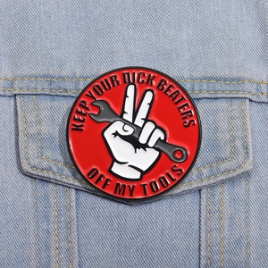 Detail showing the red enamel badge pinned on a blue denim jacket with tool-themed text
