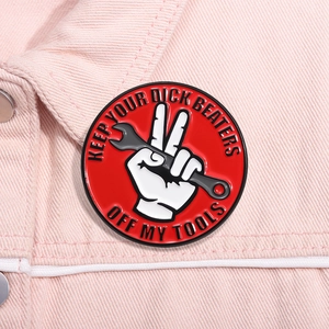 Funny red enamel tool badge on pink denim jacket featuring a wrench graphic design