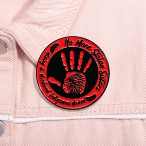 Détail du pin's émaillé rouge et noir sur veste en jean rose avec slogan MMIW