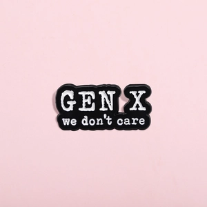 Close-up of Gen X We Don't Care enamel pin with black base and white lettering