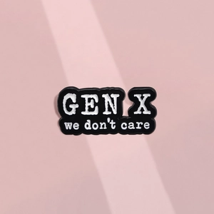 Detail of a minimalist black enamel pin with white GEN X we don't care slogan text