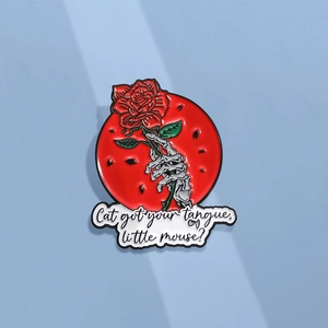 Enamel brooch with skeletal hand holding red rose and poetic quote on blue backdrop