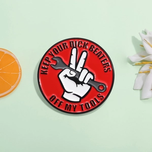 Detail of red enamel badge featuring a hand with wrench and bold warning text
