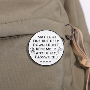 Macro shot of white enamel brooch with funny password quote on olive canvas bag